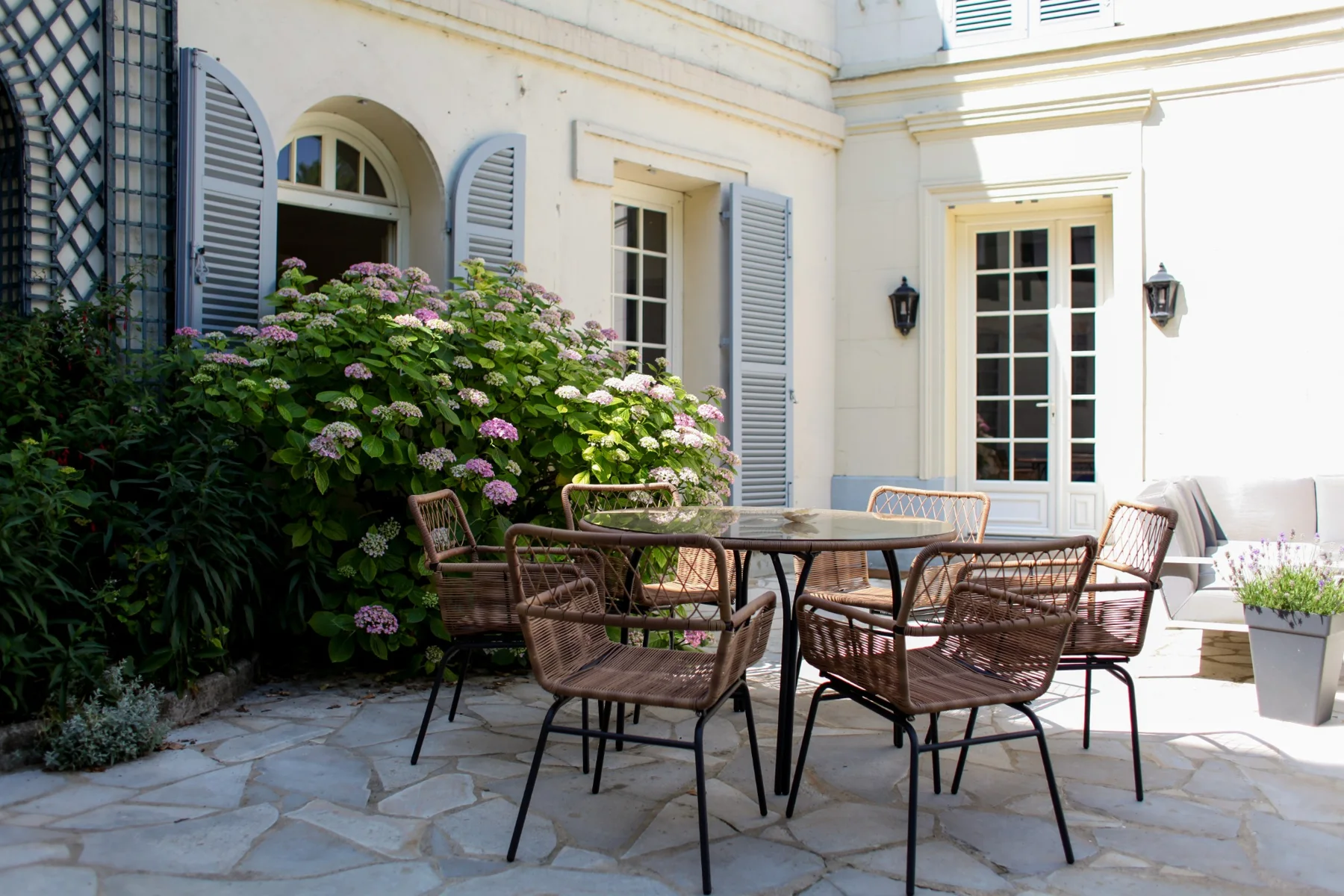 Terrasse et table de jardin devant les fenêtres de la maison